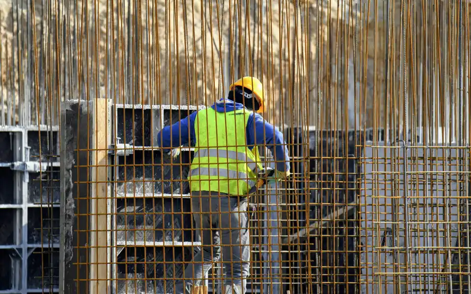 Construction worker in a high-visibility vest and hard hat on a building site, the kind of field workforce an employee location tracker helps managers keep track of