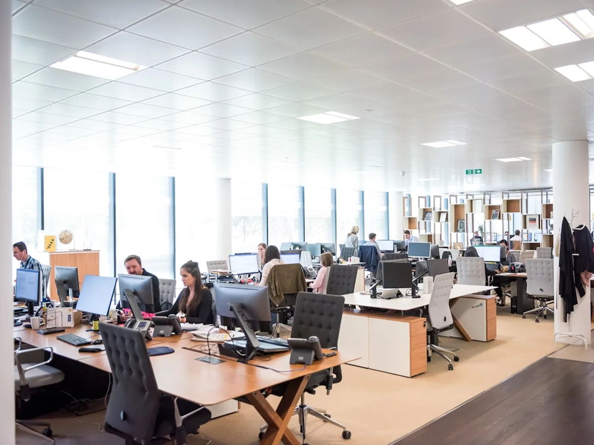 Bright open-plan office with employees working at rows of desks and monitors, representing GiveTurn's enterprise IT solutions